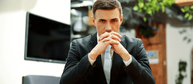 Man sitting at the conference room with hands together and thinking