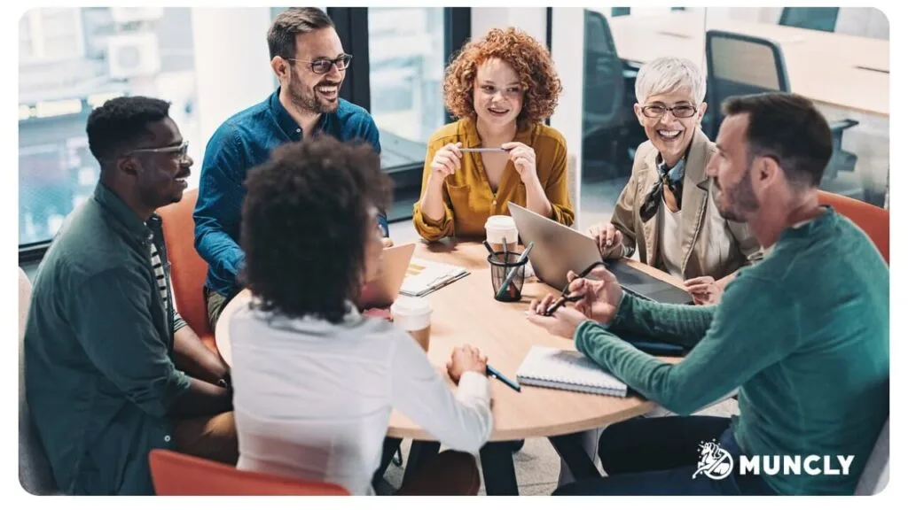 A team of six colleagues in a relaxed discussion around a round table